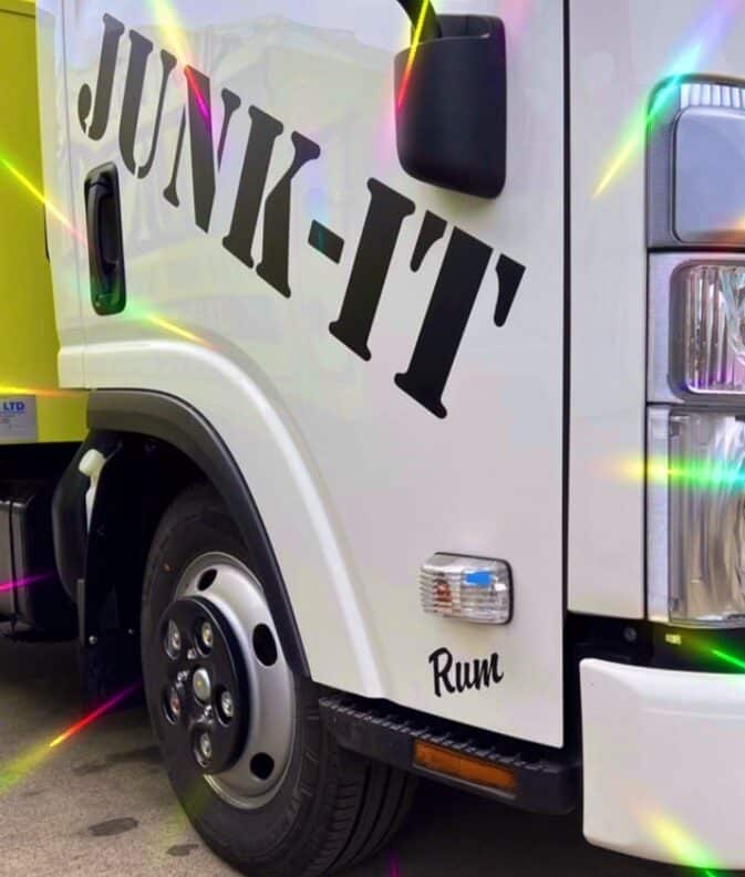 Close up picture of the side of the Junk-it truck cab with the words Junk-it and Rum in black on the white door. There are some rainbow sparkles arounf the edges for effect.